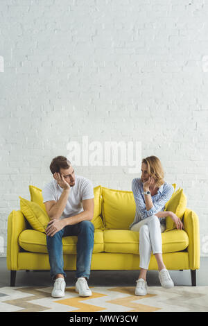 Junges Paar sitzt auf gelben Sofa in moderne Zimmer Stockfoto