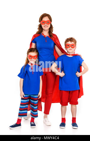 Glückliche Mutter mit niedlichen kleinen Zicklein in der Superhelden Kostüme zusammen stehen und lächelte Kamera isoliert auf weißem Stockfoto