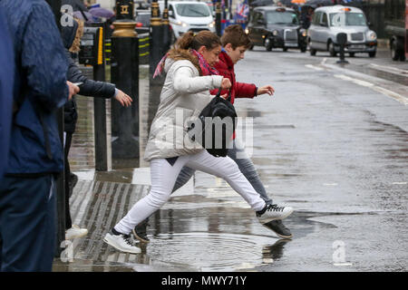 Fußgänger über eine Pfütze an der Kreuzung außerhalb des Parlaments durch Regen verursachte springen. Mit: Atmosphäre, Wo: London, Großbritannien Wann: 02. Mai 2018 Credit: Dinendra Haria/WANN Stockfoto