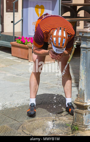 Einkehrmöglichkeit in Montisi für Radfahrer, die im Mai an der Eroica Montalcino, Siena, Toskana, Italien teilnehmen - Radfahrer, die Wasser aus dem Wasserhahn trinken Stockfoto