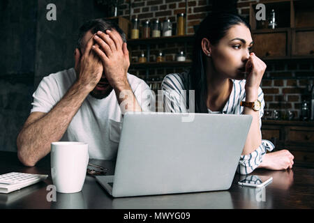 Deprimiert junges Paar sitzt auf Küche mit Laptop Stockfoto