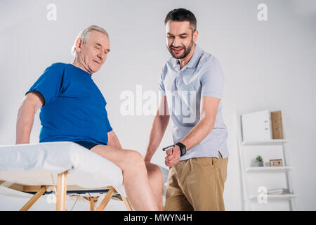 Rehabilitation Therapeut mit reflexhammer Überprüfung älterer mans Knie auf Massage Tisch Stockfoto