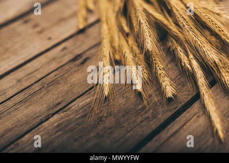 Nahaufnahme von reifem Weizen ährchen auf ländlichen Holztisch Stockfoto