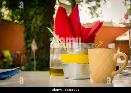 Glas, Flasche, kinfe und Servietten auf dem Tisch; Baum im Hintergrund Stockfoto