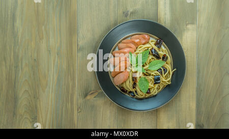 Spaghetti mit Wurst und getrocknete Paprika, würzig und scharf auf hölzernen Hintergrund, Ansicht von oben Stockfoto