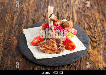 Ribeye Steak auf den Knochen, Tomahawk, serviert mit Tomaten und Eisbergsalat auf pita auf Schiefer. Stockfoto