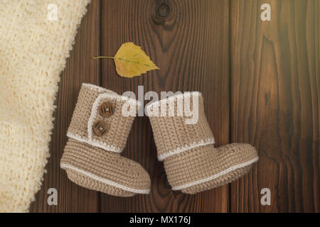 Handarbeit häkeln baby Booties und Herbst gefallen bunte Blätter auf Holz- Hintergrund, getönten Foto Stockfoto