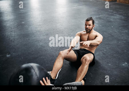 Zwei motiviert junge Menschen in Sportkleidung, zusammen mit einem medizinball auf dem Boden einer Turnhalle während einer Trainingseinheit Stockfoto