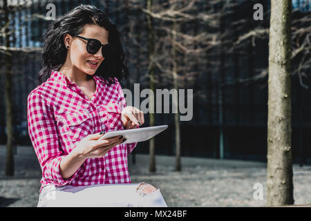 Glücklich und junge schöne Frau verwendet das Telefon. Süße Mädchen prüft, SMS, E-Mail outdoor. Konzept der Lifestyle, Lebensfreude. Weibliche genießt online einkaufen. Stockfoto