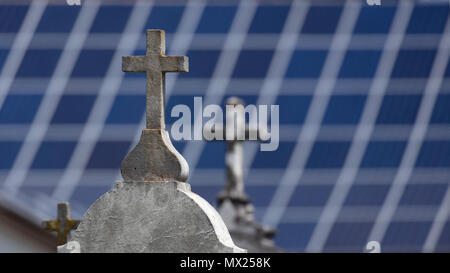 Stein Kreuze auf Gräber mit unscharfen Solarzellen im Hintergrund Stockfoto