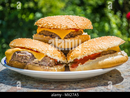 Platte voll von Cheeseburger in Garten im sonnigen Mittag Stockfoto