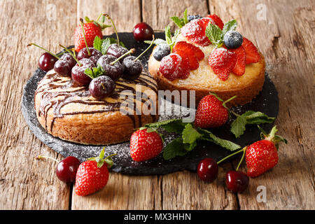 Keks Kuchen mit Schokolade, Staubzucker, Minze dekoriert, und im Sommer Beeren close-up auf einer Schiefertafel board. Horizontale Stockfoto