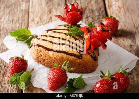 Celebratory mini Kuchen in der Form von Herzen, mit Schokolade und Erdbeer Rosen in der Nähe eingerichtet - auf den Tisch. Horizontale Stockfoto