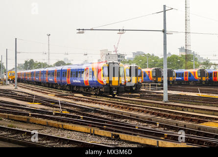 South Western Railway Züge in Blau, Gelb und Rot Lackierung in die Bahn Gleisanschluss an das Depot in Clapham Junction Station, London, UK Stockfoto