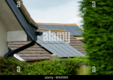 Isolierter, flacher Fokus von neu installierten Solarmodulen auf einem Einfamilienhaus. Ebenfalls im Blick ist ein weiteres Haus mit Sonnenkollektoren. Stockfoto