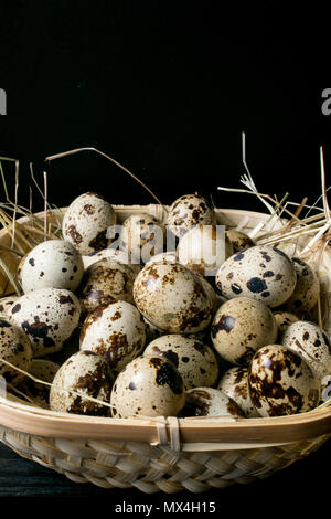 Wachtel Eier in ein Nest. Gesunde Ernährung Konzept. Haufen Wachteleier im Heu auf dunklem Hintergrund Stockfoto