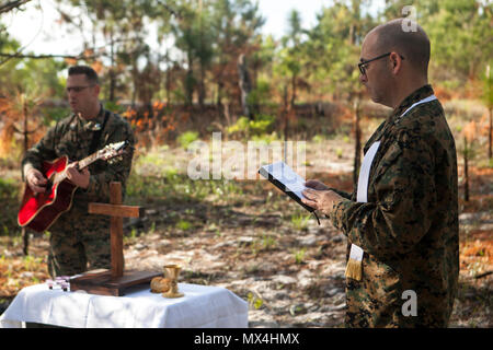 Marine Lieutenant Commander Chris Stanfield, der Kaplan für besondere Zwecke Marine Air-Ground Task Force - Southern Command, hält eine Protestantische, während Kapitän Jeremy Croft, die SPMAGTF-SC Public Affairs Officer, die Gitarre bei der allgemeinen Übung II Ausbildung bei der Marine Corps Base Camp Lejeune in North Carolina, 30. April 2017 spielt. Marines sind die Möglichkeit, religiöse Dienste, während in einer expeditionary Umwelt mit Unterstützung der U.S. Navy Seelsorger Besuchen angeboten. Stockfoto