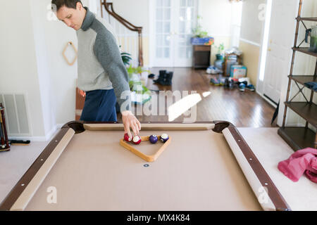 Innen im Haus Haus mit Pool Billard Tisch im Wohnzimmer, junger Mann im kalten Winter Pullover, Bälle, Spiel, Dreieck Stockfoto