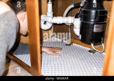 Mann Inverkehrbringen Schutzfolie blatt Innen auf Holz Schränke unter der Spüle mit Händen in der Küche Schubladen Stockfoto