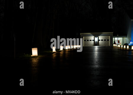 Heiligabend Kerzenlicht Flamme beleuchtete in Papiertüten mit Garage in der Nacht in Zeile Futter Straße Straße Dekoration während der Ferien Stockfoto