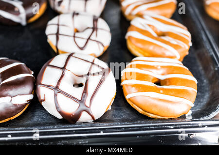 Braun Schokolade, Karamell und weiße Zuckerglasur Donuts mit Löchern closeup auf Bäckerei Fach, frittierter Vanille, lecker lecker Stockfoto