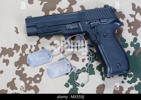 Sig sauer Hand Waffe und Dog Tags auf Wüste getarnt Hintergrund Stockfoto