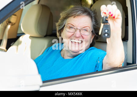 Gerne ältere Frau sitzt im neuen Auto Halten der Tasten. Stockfoto