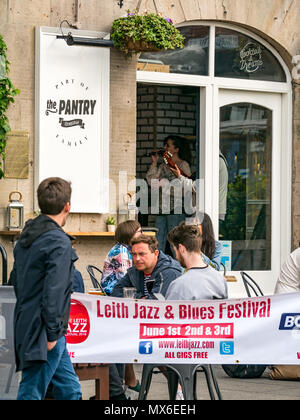 Leith Jazz & Blues Festival live Musik in Restaurants und Bars, in denen das Wasser von Leith, 3. Juni 2018. Die Shore, Leith, Edinburgh, Schottland, Vereinigtes Königreich. Die Jazz und Blues Festival findet über 3 Wochenenden. Die Menschen drängen sich im Bürgersteig Tische der Restaurants und Bars entlang der Wasser des Leith Hören genießen Sie den kostenlosen live Musik. Die Leute an den Tischen vor einer Bar namens der Speisekammer mit dem Festival banner Sitzung angezeigt. Stockfoto