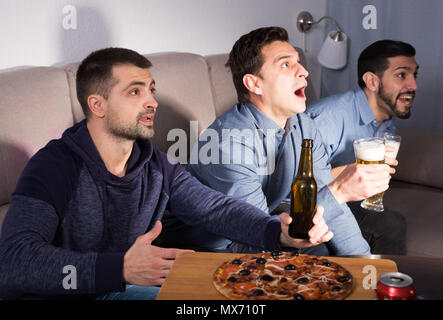Erhaben männliche Freunde tv gemeinsam zu Hause, Bier und Pizza genießen. Stockfoto