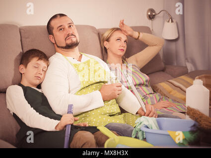 Müde Eltern mit Sohn für die Reinigung auf der Couch zu Hause ruhenden gekleidet Stockfoto