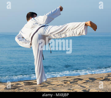 Jungen Kerl training Karate Posen am Strand im sonnigen Morgen im Freien Stockfoto