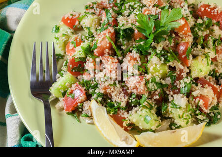 Tabbouleh Salat mit Couscous in grüne Platte auf rustikalen Tisch Stockfoto