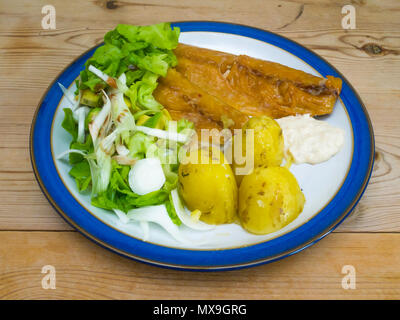 Eine geräucherte Makrele Salat mit neuen Kartoffeln und Meerrettich Sauce auf einem blauen und Pfingstmontag Platte auf einen hölzernen Tisch. Stockfoto