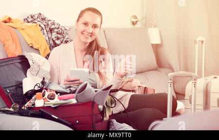 Lächelnde Frau kauf Hotel oder Ticket im Internet mit Laptop und Karte zuhause Stockfoto