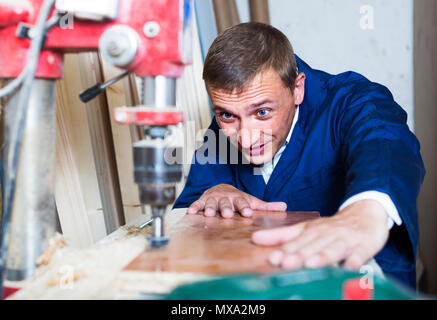 Kaukasische workman bohren Bohlen über elektrische Schraubendreher in der Werkstatt Stockfoto