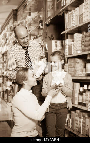 Freundliche spanische Familie von drei Personen wählen Sie Elemente in der Apotheke Stockfoto