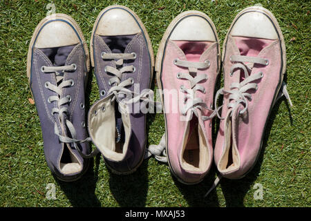 Ein paar rosa und blau Sneakers auf dem Rasen in der Sonne, vielleicht die männlichen und weiblichen Stockfoto