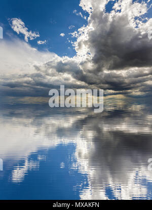 Fantastische Aussicht auf helle weiße und dunkle Puffy clouds beleuchtet von Sun gegen den tiefblauen Himmel im Wasser widerspiegelt. Schönheit und Kraft der Natur, Umwelt pro Stockfoto
