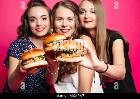 Hübsche Freundinnen mit saftigen Hamburger. Stockfoto