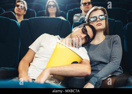 Junger Mann mit Popcorn im Kino. Langweilig film Konzept, Leute beobachten Film Stockfoto