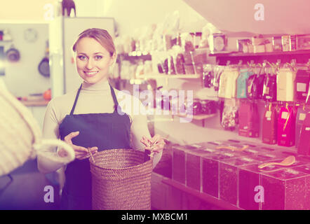 Lächelnde blonde Frau mit Schürze und Verkauf von Nüssen und Trockenfrüchten in organischen Shop Stockfoto