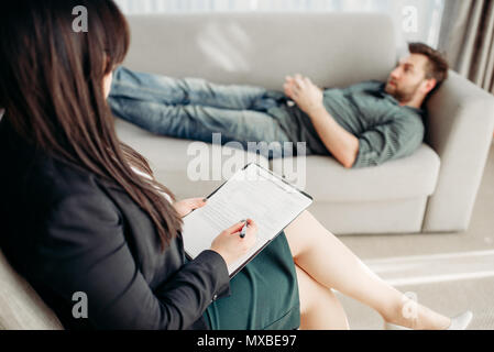 Männliche Patienten bei der Psychologe Rezeption, Stress. Ärztin schreibt Notizen in Notepad, professionelle Psychologie Stockfoto