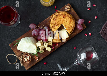 Käseplatte mit verschiedenen Käsesorten, Trauben, Nüsse über schwarzen Hintergrund, kopieren. Italienischen Käse und Obstteller mit Honig und Wein. Stockfoto