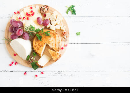 Käseplatte mit verschiedenen Käsesorten, Trauben, Nüsse über weiß Holz- Hintergrund, kopieren. Italienischen Käse und Obstteller. Stockfoto