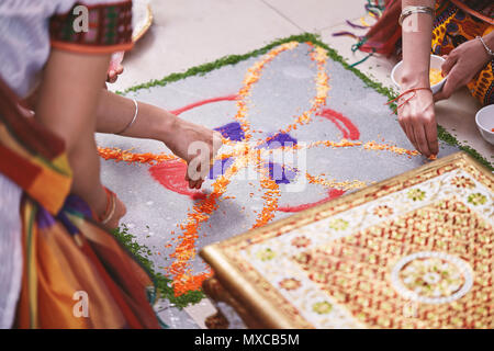 Frauen hilft Färbung Tradition bunte Reis Kunst oder sand Kunst (RANGOLI) auf dem Boden mit Papier Muster mit trockenem Reis und Mehl mit farbigen aus Stockfoto