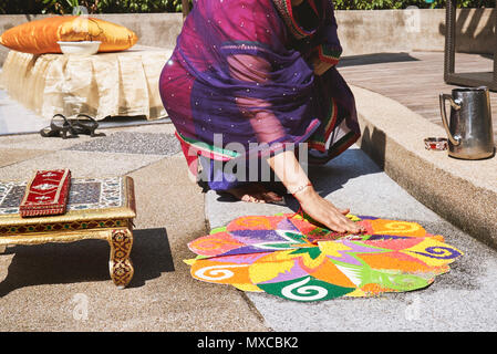 Frauen verzieren und färben Tradition bunte Reis Kunst oder sand Kunst (RANGOLI) auf dem Boden mit Papier Muster mit trockenem Reis und Mehl mit Colo Stockfoto