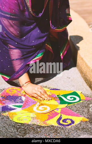 Frauen verzieren und färben Tradition bunte Reis Kunst oder sand Kunst (RANGOLI) auf dem Boden mit Papier Muster mit trockenem Reis und Mehl mit Colo Stockfoto