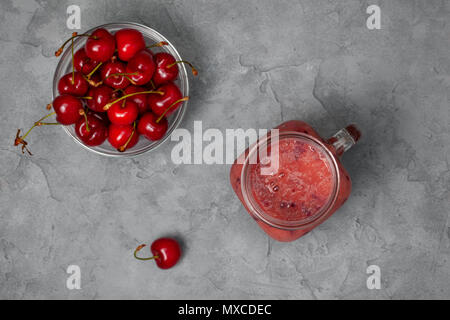 Cherry Smoothie in Mason jar auf grauem Beton Hintergrund. Ansicht von oben Stockfoto