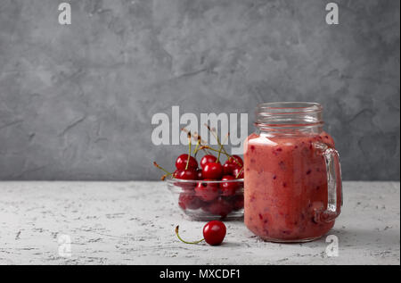 Cherry Smoothie in Mason jar auf grauem Beton Hintergrund Stockfoto