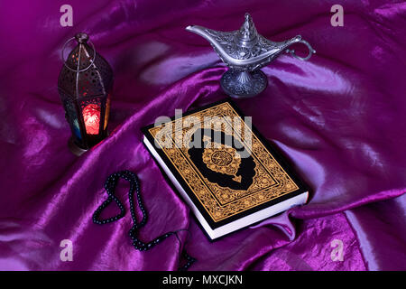 Heiligen islamischen Buch Koran auf lila Seide mit einem Rosenkranz, Laternen und Ägypten Aladins Wunderlampe - Ramadan Kareem/Eid al Fitr Konzept. Stockfoto